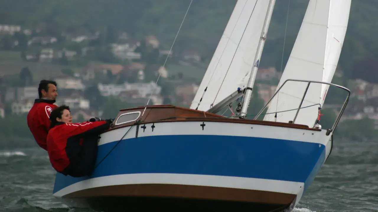 Couple en action sur un voilier transportable hauturier, profitant d'une navigation par temps frais.
