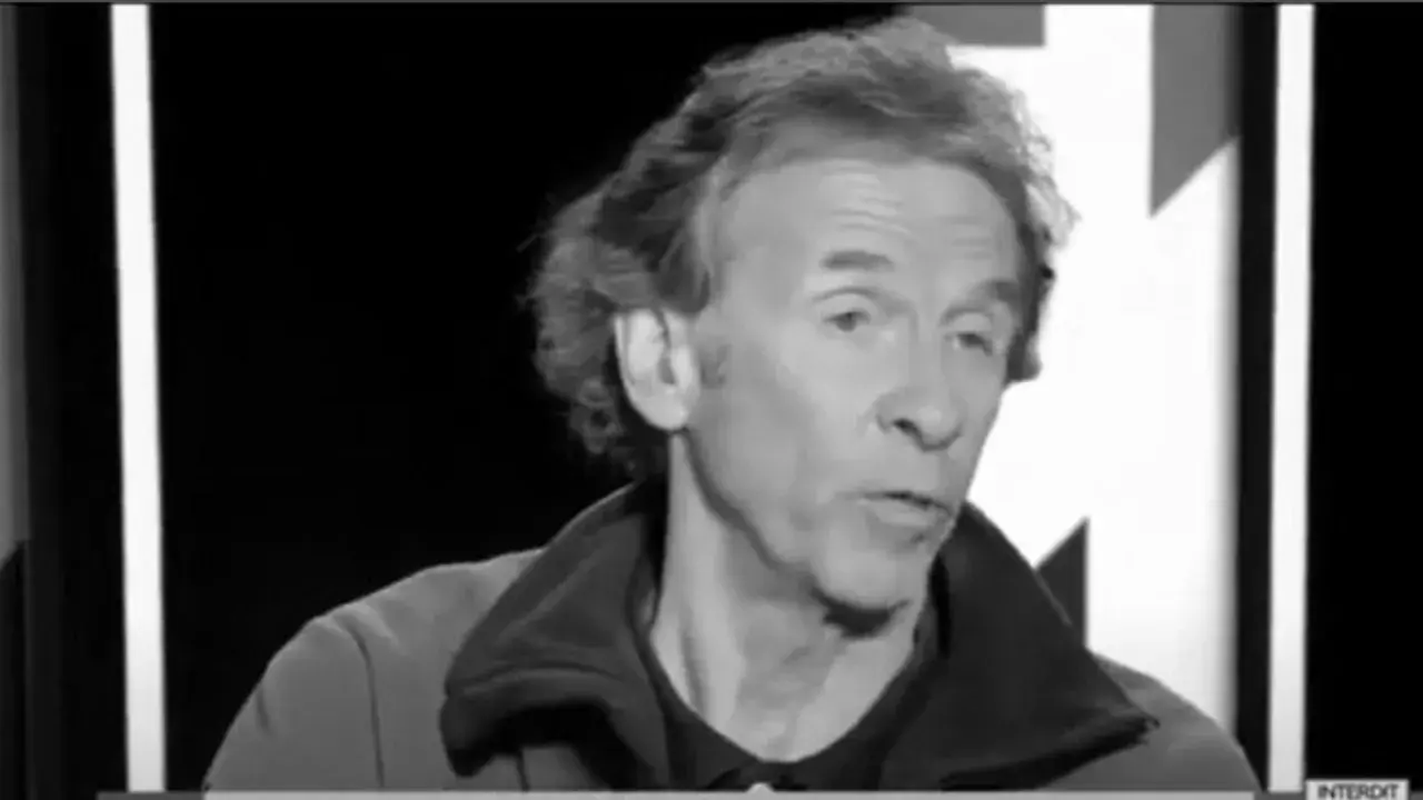 Portrait en noir et blanc d'Éric Loizeau, homme aux cheveux ondulés, parlant dans un micro.
