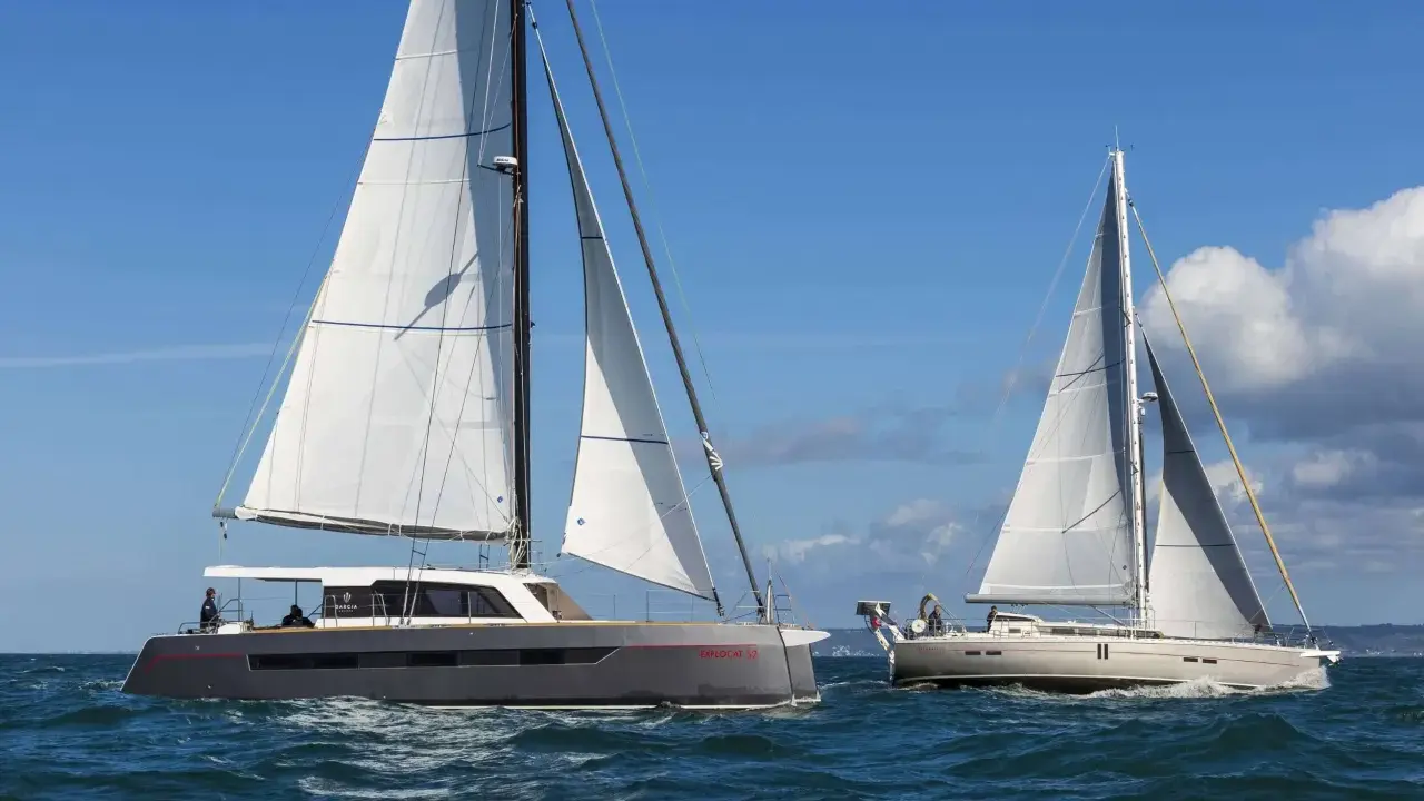 Deux grands voiliers naviguent sur une mer bleue sous un ciel clair.
