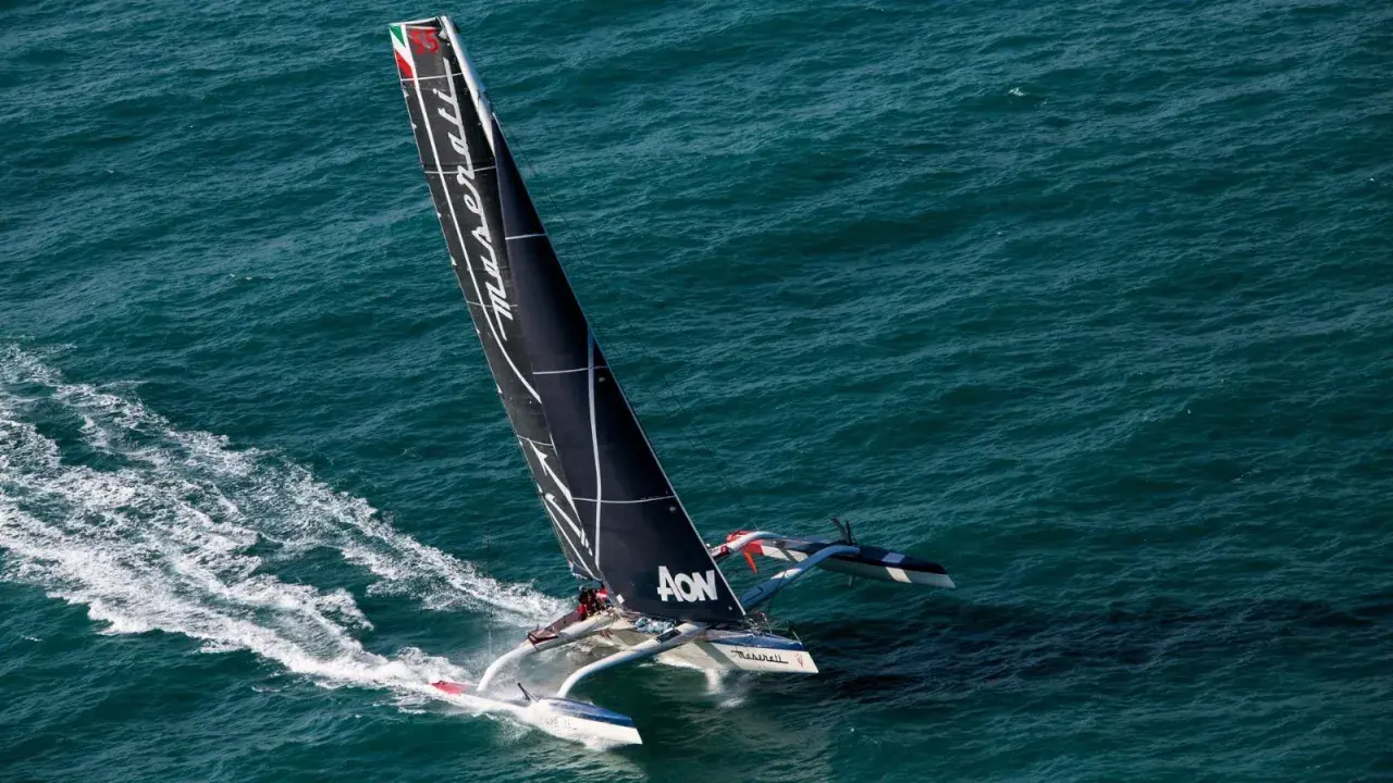 Le trimaran Maserati, skippé par Giovanni Soldini, fend les vagues bleues, laissant une traînée d'écume.