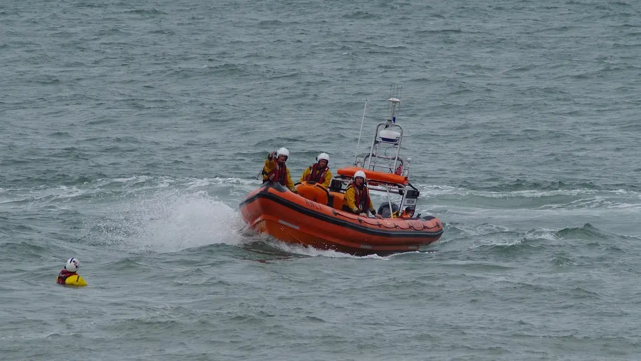 Bateau de sauvetage orange avec équipage en action. Une personne dans l'eau, une fusée de détresse bateau obligatoire est essentielle.