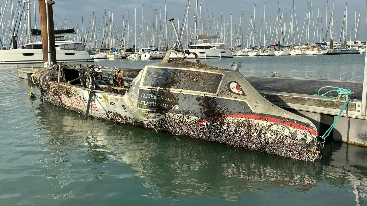 Un bateau coulé, couvert de coquillages, est amarré dans un port. Le nom "Talisker Whisky Atlantic Challenge" est visible.