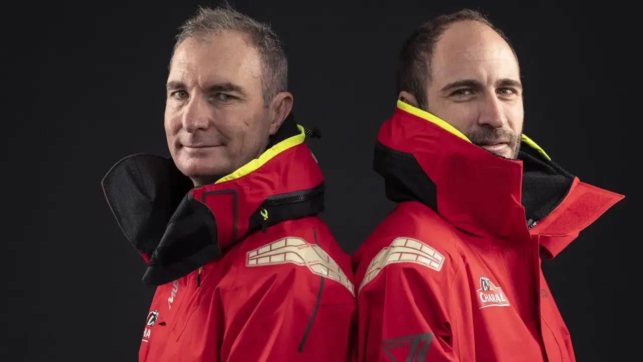 Morgan Lagravière et son coéquipier, deux marins en veste rouge, prêts pour l'aventure en mer.