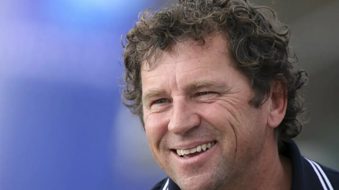 Lionel Lemonchois, skipper souriant, cheveux bouclés, sur fond bleu.