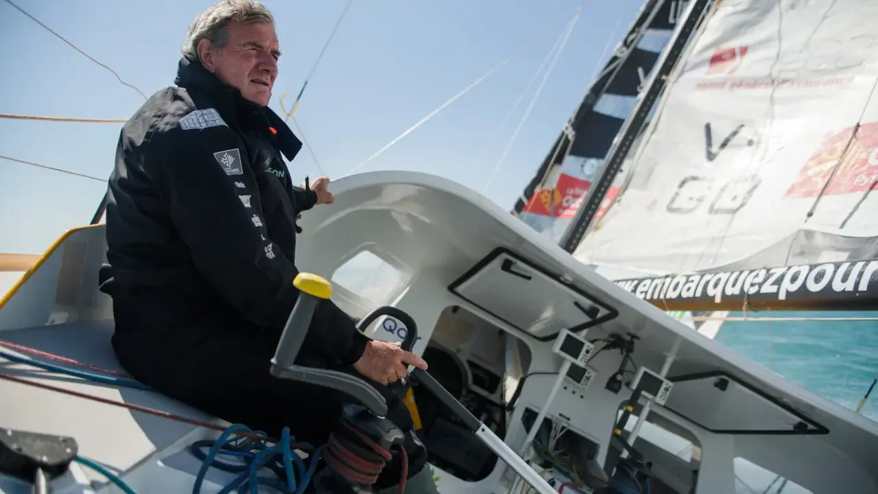 Un homme expérimenté, kito de pavant, tient la barre d'un voilier, concentré sur la course.