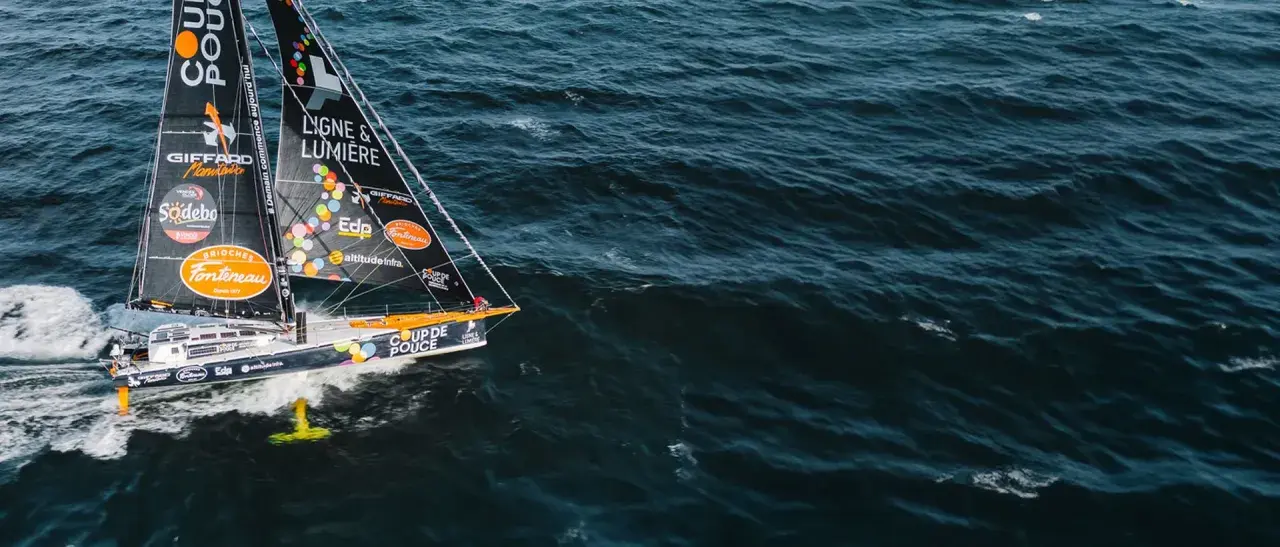 Voilier "Coup de Pouce" naviguant sur une mer agitée, avec le nom "Manuel Cousin" visible sur la voile.
