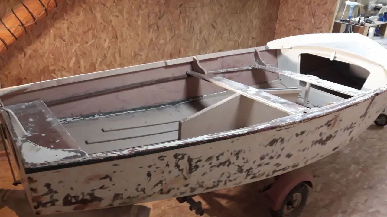 Un dériveur Caravelle polyester en cours de restauration, sur sa remorque. La coque est décapée, prête pour une nouvelle peinture.