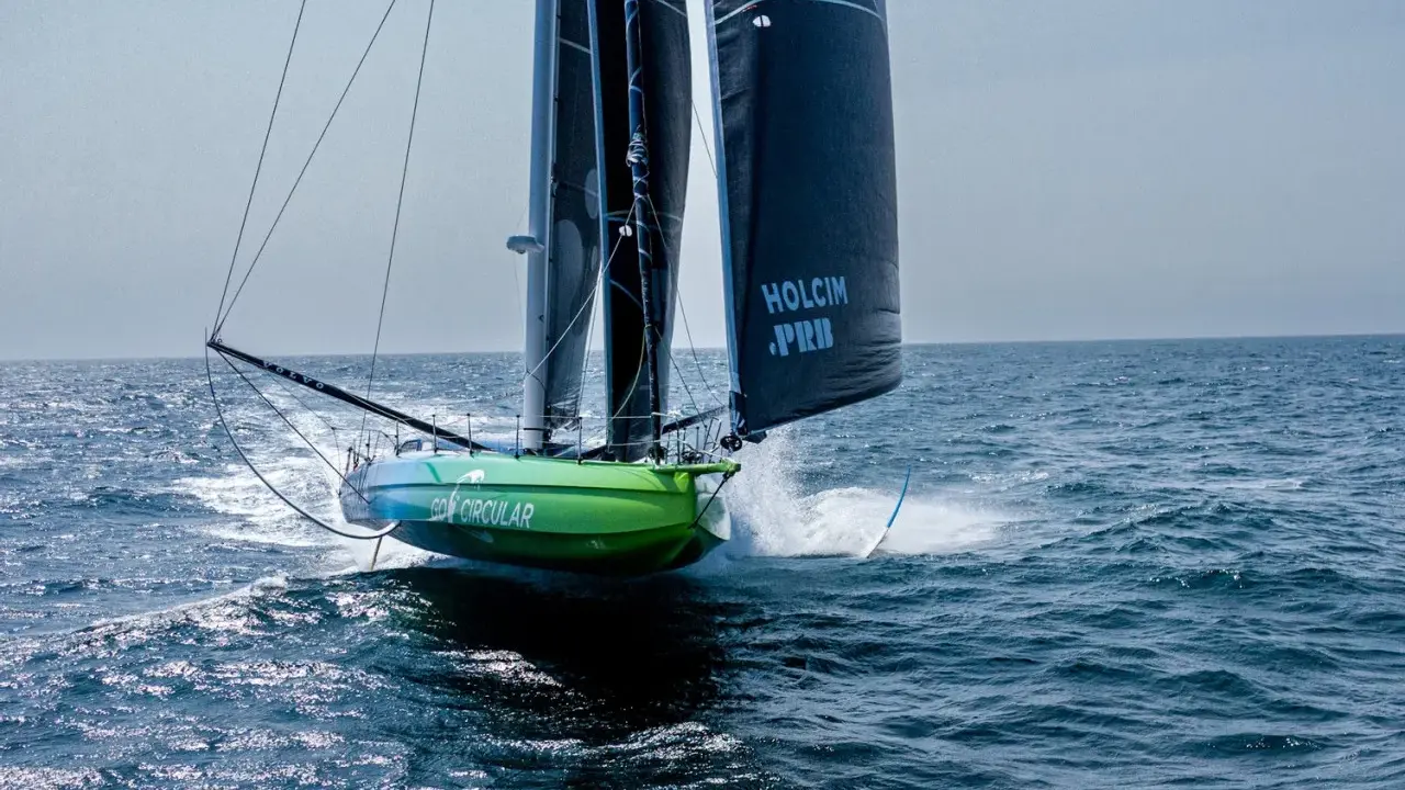 Voilier vert et bleu "Go Circular" naviguant à pleine vitesse, voiles noires marquées "Holcim PRB". Un design de Guillaume Verdier.