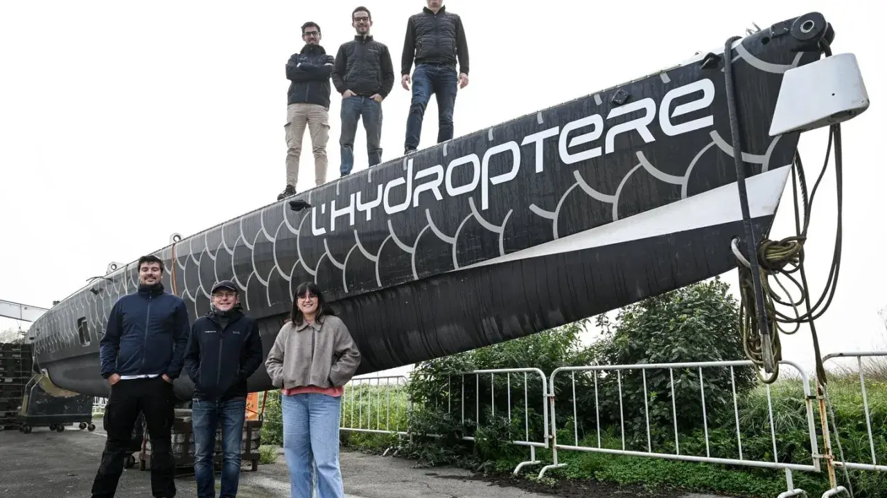 L'équipe pose fièrement devant l'hydroptère 2.0, un navire futuriste prêt à fendre les flots.