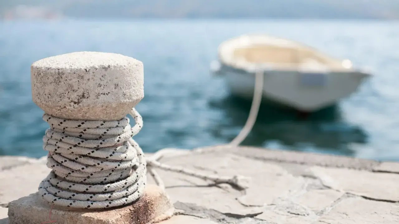 Un cordage est enroulé autour d'une borne en pierre sur un quai, prêt pour le prochain pendille bateau.