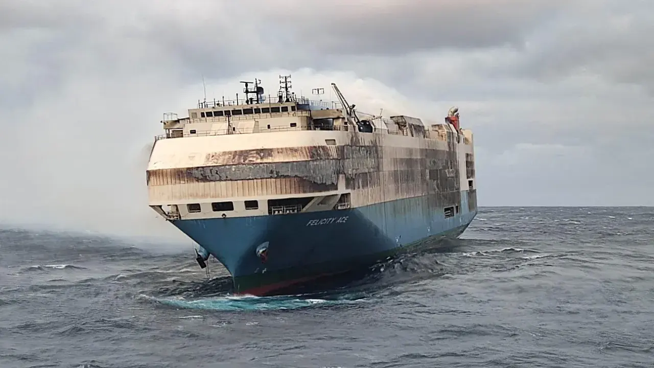 Le cargo Felicity Ace, en feu, dérive sur une mer agitée. De la fumée s'échappe de ses ponts supérieurs.