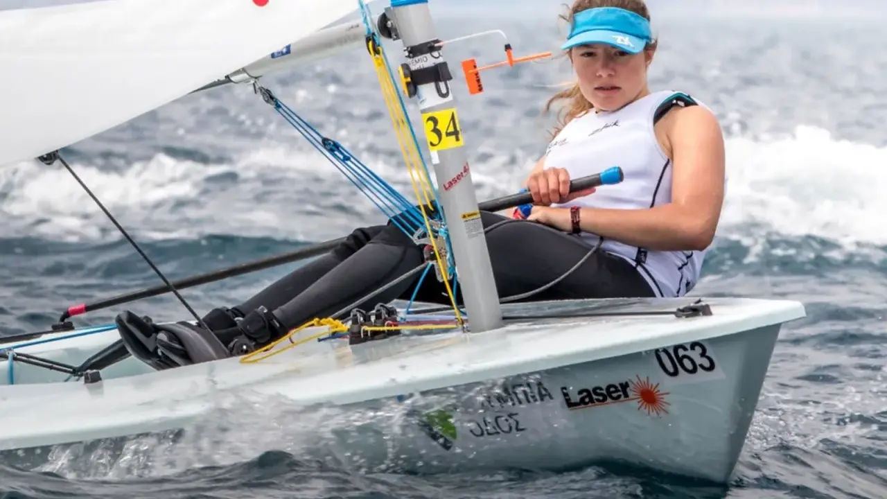 Jeune femme concentrée naviguant en deriveur solo, le bateau #063 fend les vagues.
