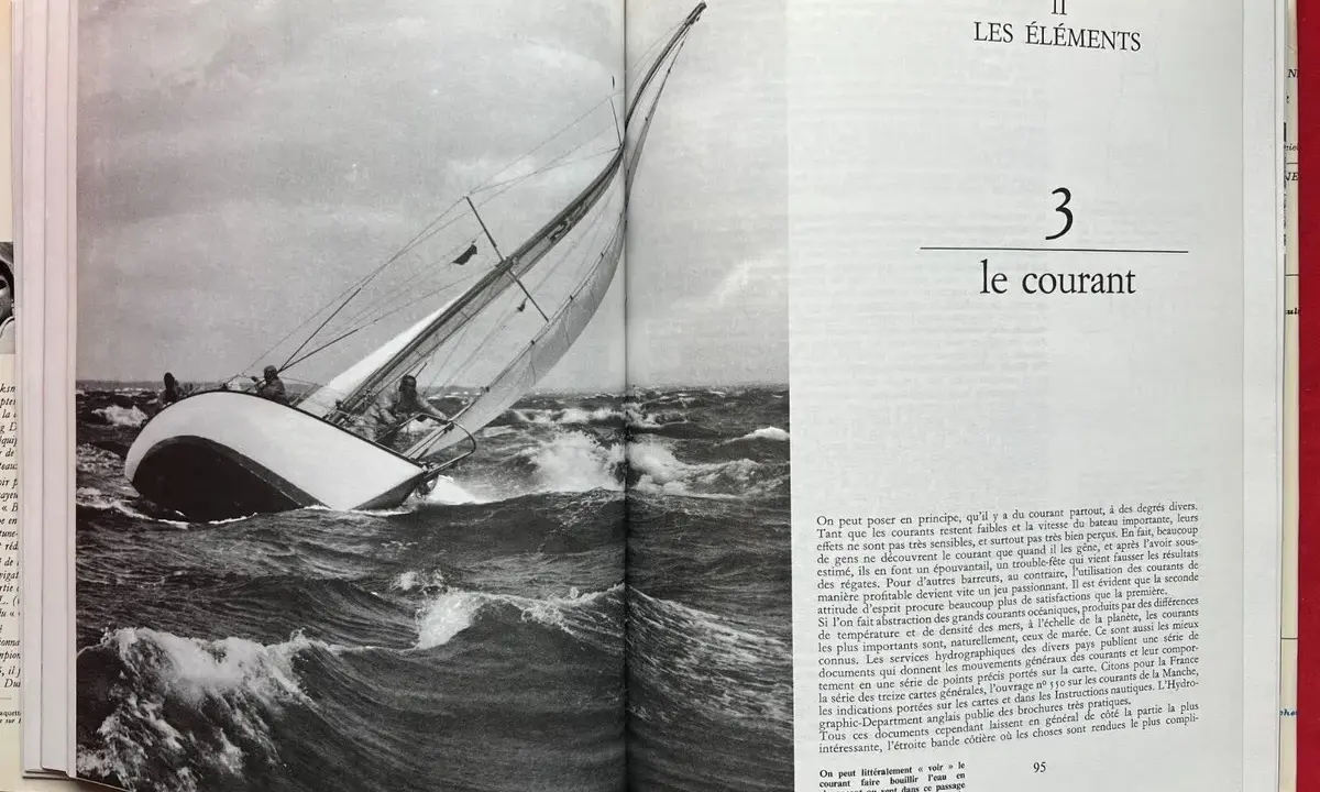 Un voilier navigue dans une mer agitée, ses voiles gonflées par le vent. Alain Gliksman, passionné de voile, admire cette scène.