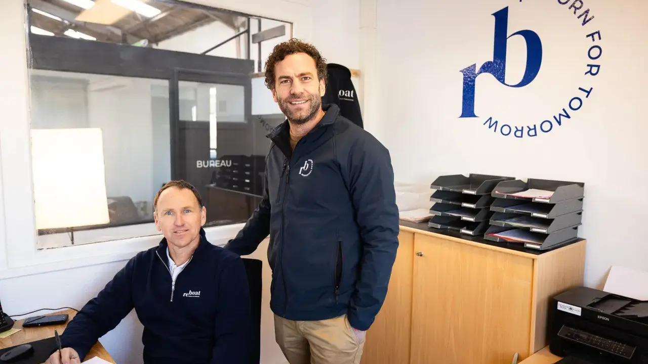 Dimitri Caudrelier et son collègue dans leur bureau, avec le logo "Reborn for Tomorrow" au mur.