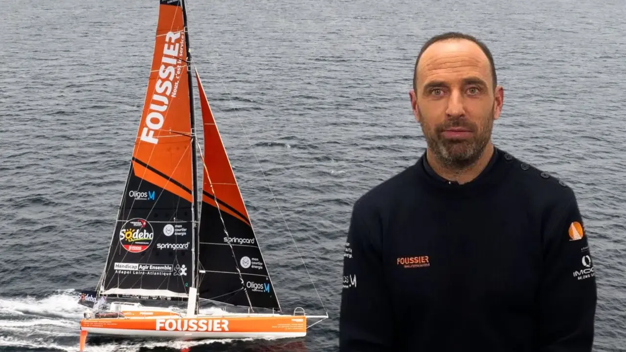 Sébastien Marsset, skipper du voilier Foussier, prêt pour la course. Le bateau orange et noir fend les vagues.