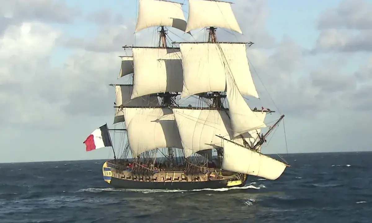 La frégate Hermione, fierté de la marine française, navigue majestueusement sur l'océan, ses voiles gonflées par le vent.