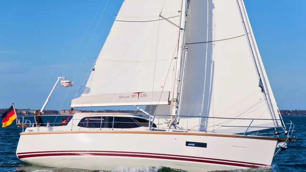 Voilier blanc Sirius 35 DS naviguant sur une mer bleue, avec le drapeau allemand à l'avant.