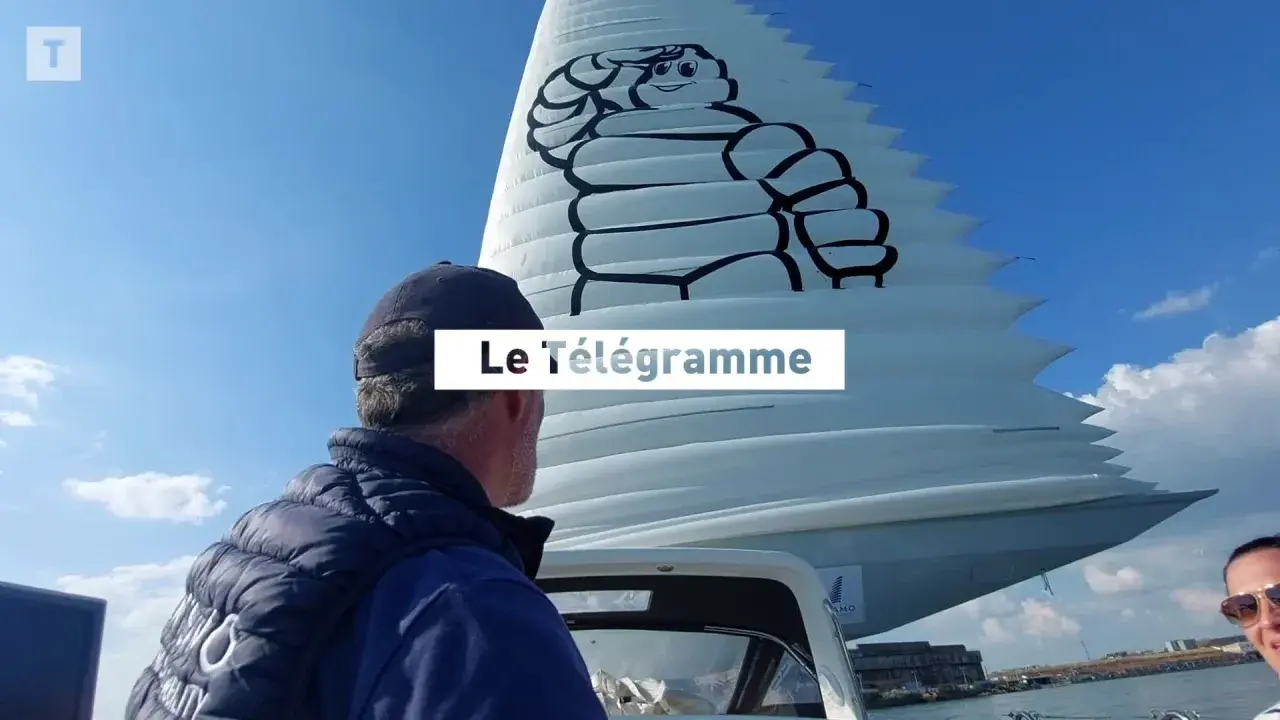 Un homme regarde une voile géante ornée du logo Michelin. Le Télégramme est affiché sur la voile.