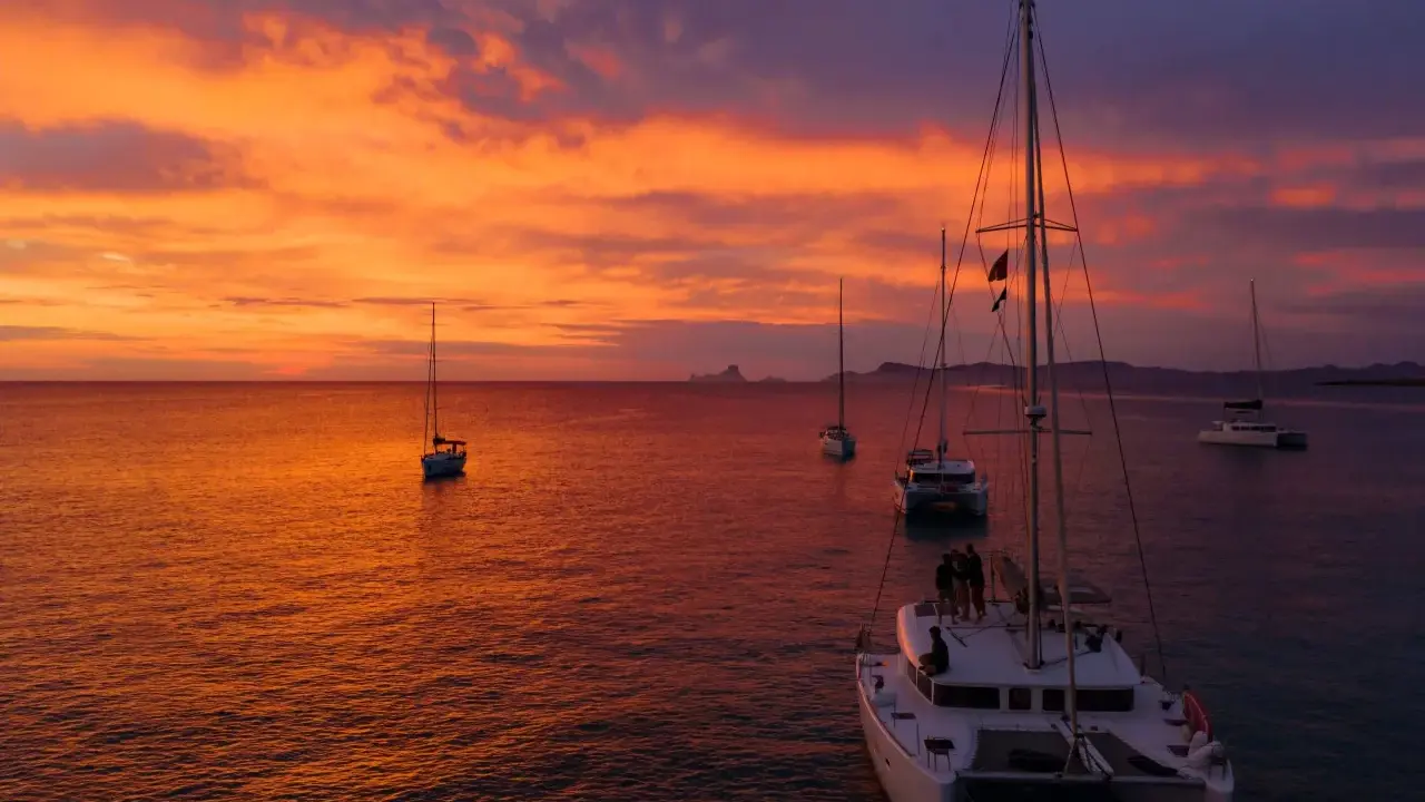 Coucher de soleil sur la mer avec des voiliers. Le tarif destruction bateau est une préoccupation pour certains, mais ici, la beauté règne.