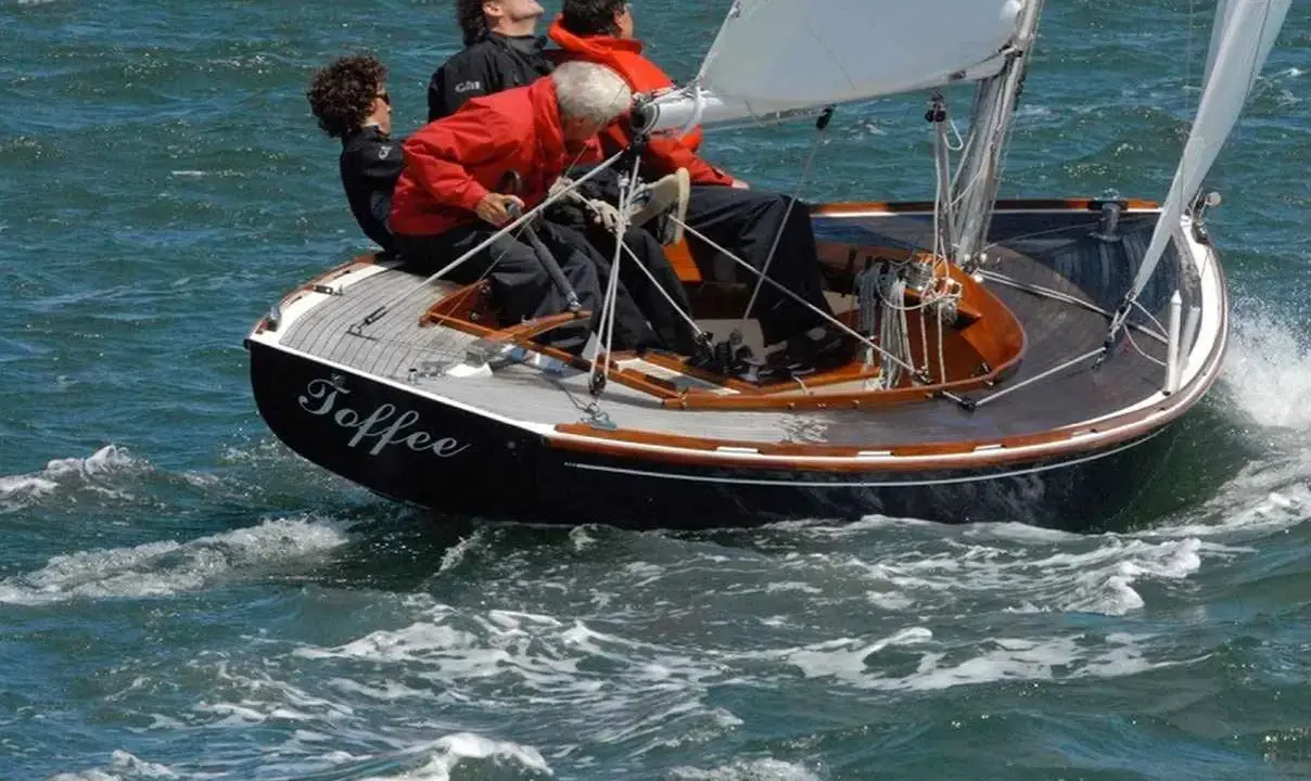 Le voilier "Toffee" navigue sur une mer agitée, quatre personnes à bord profitent de la balade.