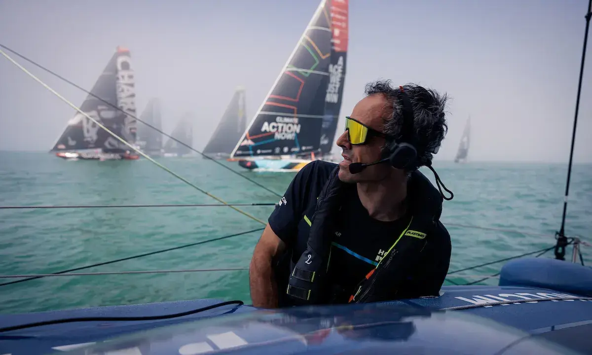 Franck Cammas, concentré, navigue en tête d'une flotte de voiliers dans le brouillard.