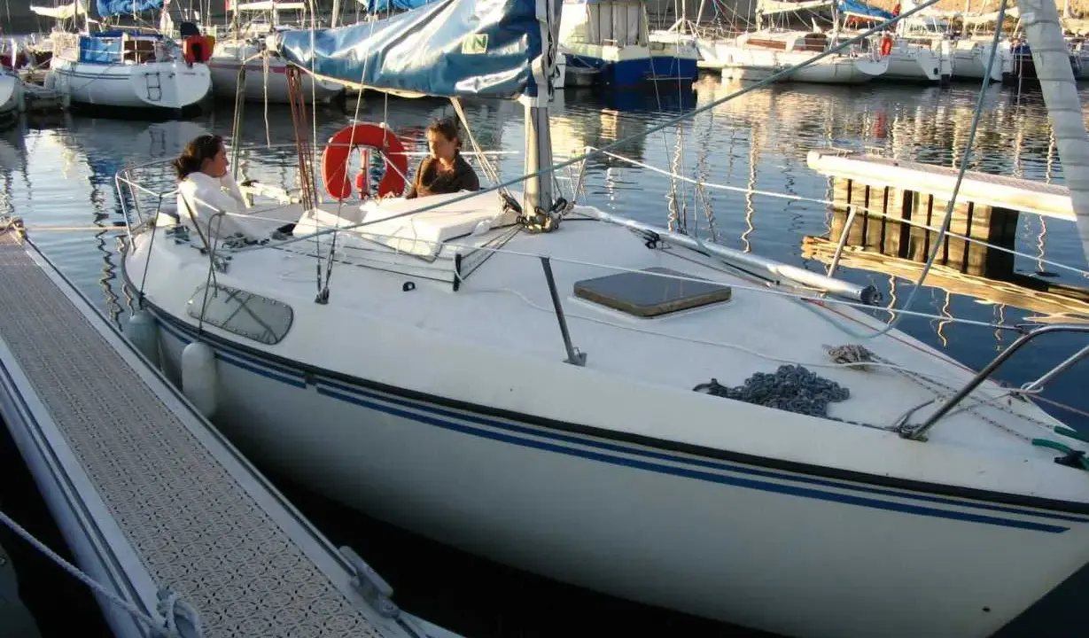Deux personnes sur un voilier blanc, un Kelt 620, dans un port. Les avis sur ce bateau sont positifs.