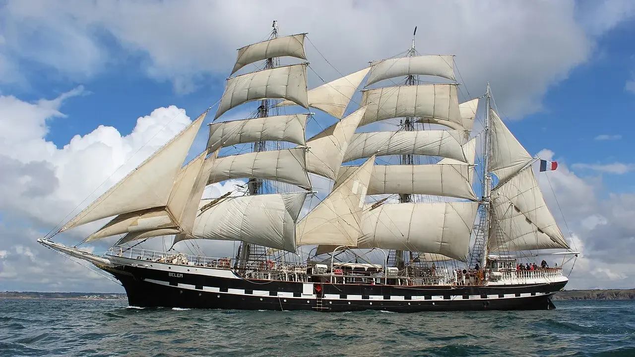 Le Belem, majestueux trois-mâts, navigue fièrement sous un ciel bleu et nuageux, rappelant les grandes traversées vers Bayonne.