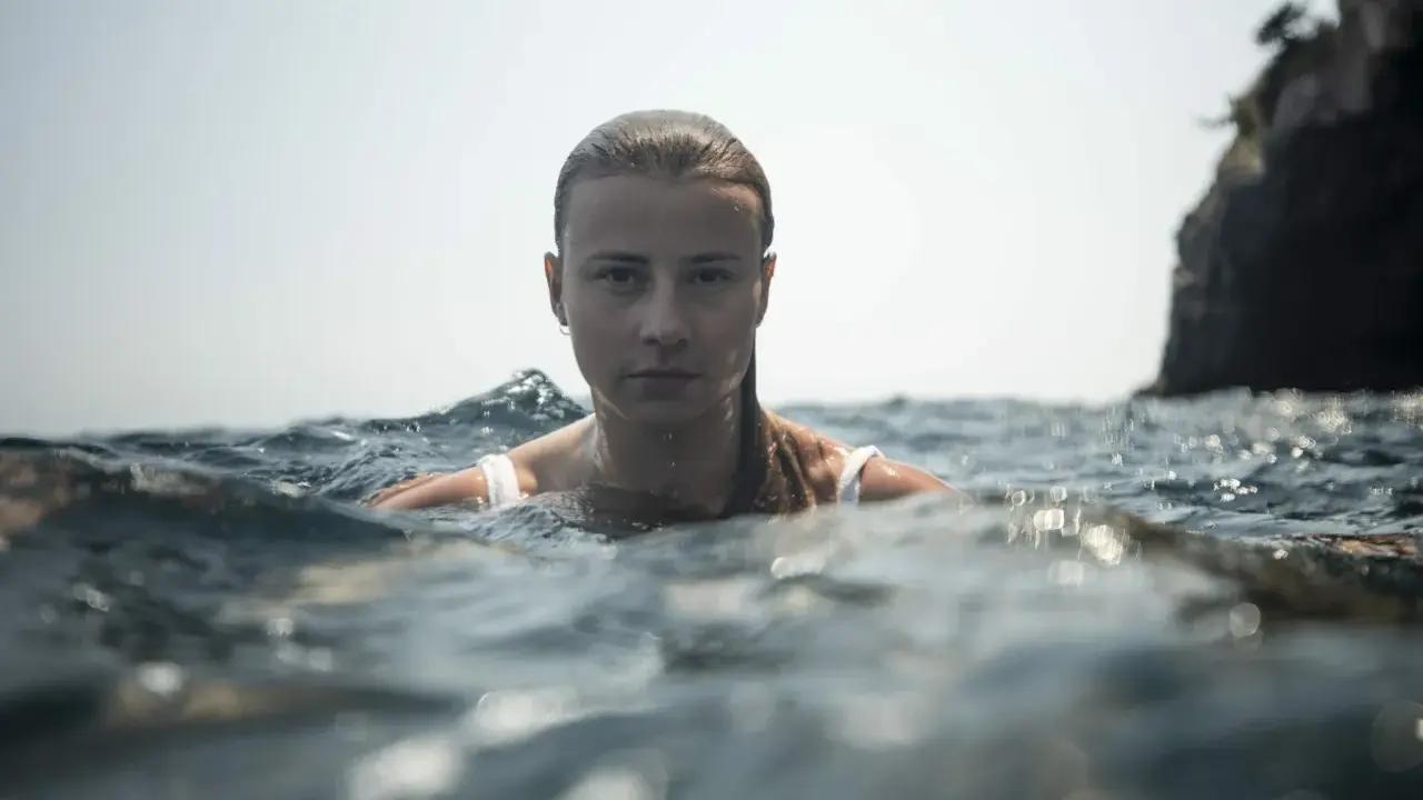 Marion Moriceau, le visage émergeant des vagues, le regard intense, baignée par la lumière du jour.
