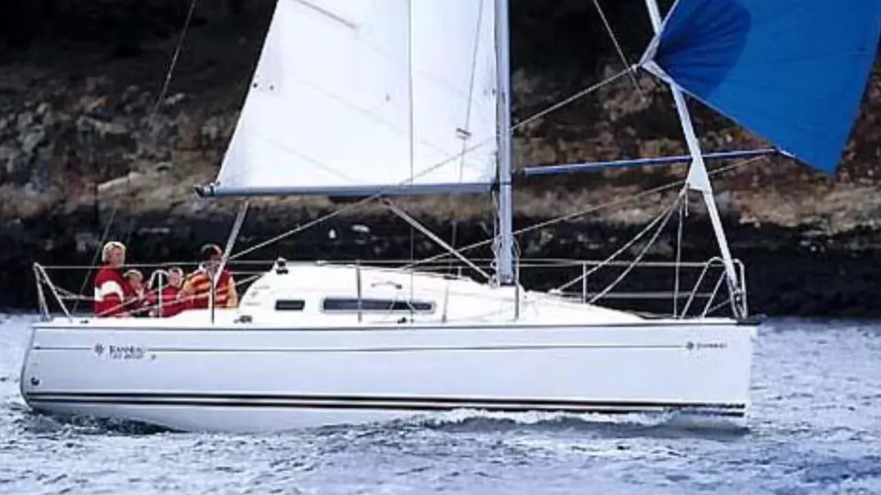 Un voilier Sun Odyssey 26 navigue sur une mer calme, avec des personnes à bord. Les avis sur ce bateau sont généralement positifs.