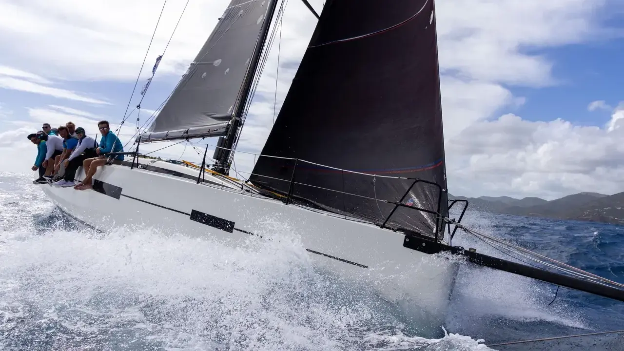 Équipage sur un voilier blanc, gery trentesaux, naviguant sur une mer agitée sous un ciel nuageux.