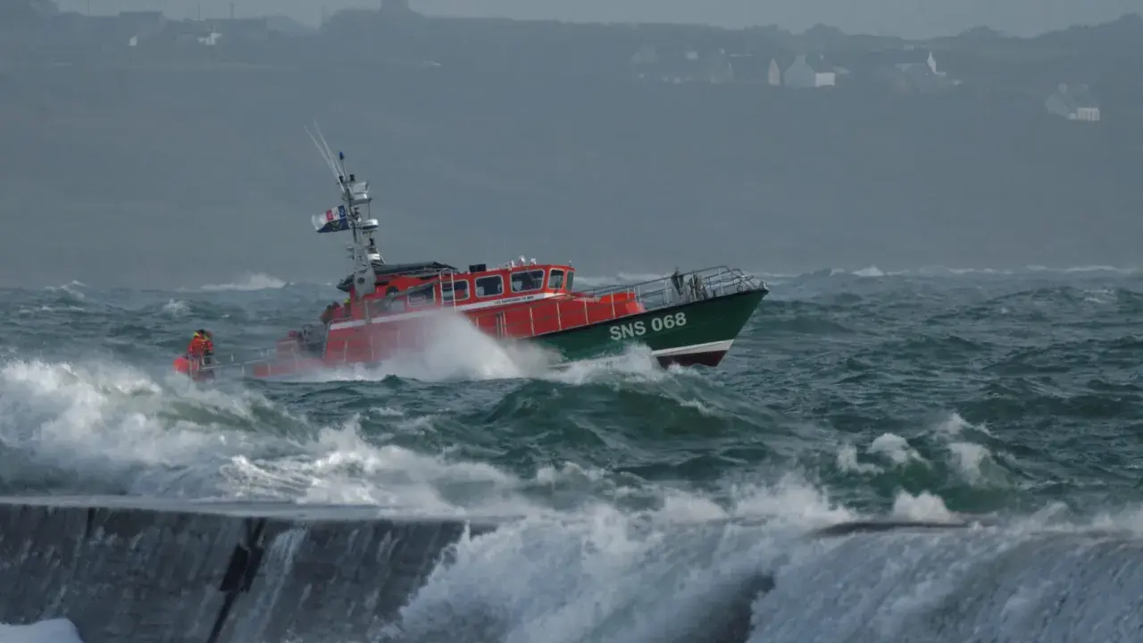 Bateau de sauvetage SNS 068 naviguant dans une mer agitée, affrontant la tempête. Les vagues déferlent sur la proue.