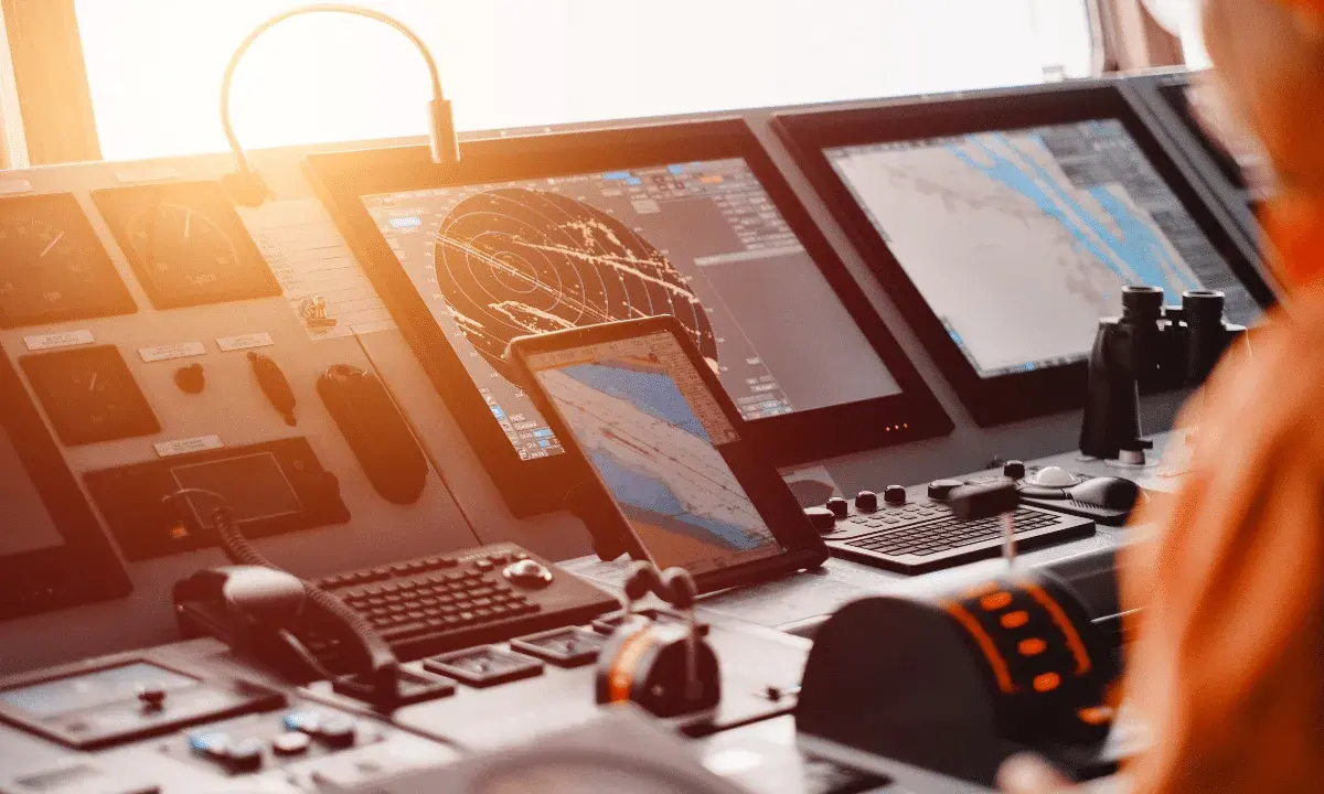 Tableau de bord d'un navire avec écrans radar et cartes maritimes. La **priorité voile** est assurée par ces technologies de navigation avancées.