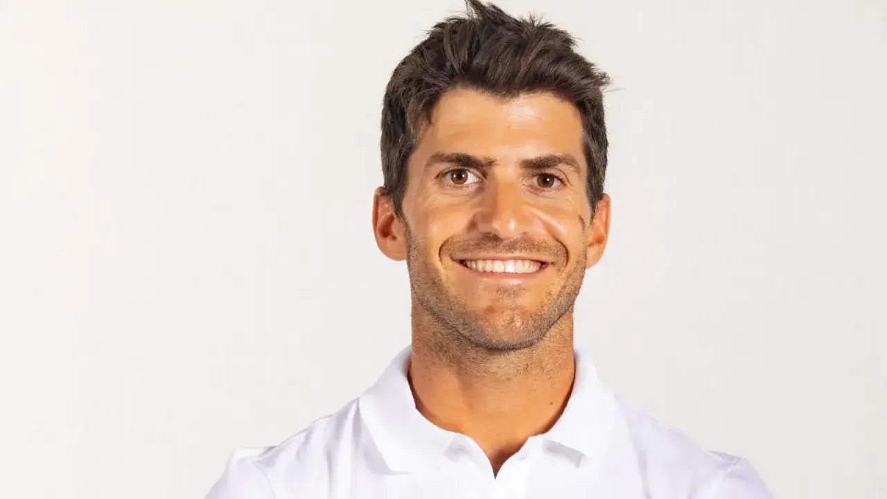 Portrait souriant de Kévin Peponnet, athlète français en polo blanc, sur fond clair.