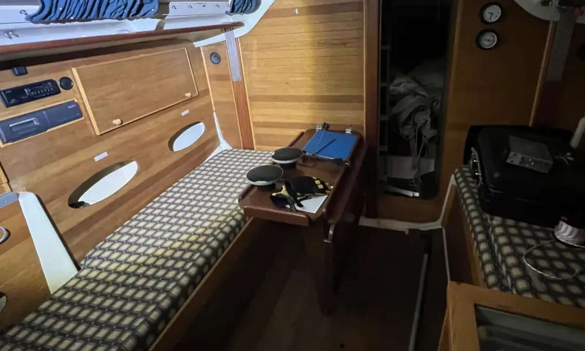 Intérieur d'un voilier Trident 80. Banquette, table pliante, rangement et couchette.