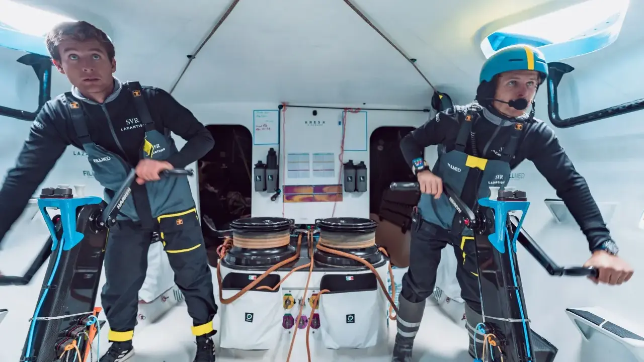 Deux marins concentrés sur le pont d'un bateau, prêts pour la course **Kerkena 6.1**.
