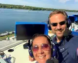 Adrien Hardy et sa collègue commentent une course sur un lac.