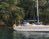 Voilier blanc ancré près d'une côte luxuriante et verdoyante. Le trismus 32 semble prêt pour une aventure tropicale.