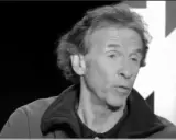 Portrait en noir et blanc d'Éric Loizeau, homme aux cheveux ondulés, parlant dans un micro.