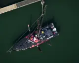 Le voilier MACSF, piloté par Corentin Horeau, est hissé hors de l'eau par une grue.