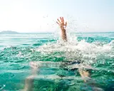 Main d'une personne émergeant de l'eau, éclaboussures vives. Un appel à l'aide pour sauver quelqu'un de la noyade.