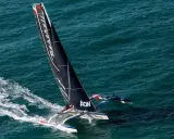 Le trimaran Maserati, skippé par Giovanni Soldini, fend les vagues bleues, laissant une traînée d'écume.
