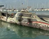 Un bateau coulé, couvert de coquillages, est amarré dans un port. Le nom "Talisker Whisky Atlantic Challenge" est visible.
