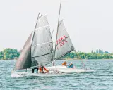 Deux voiliers d'aviron modernes naviguent sur un lac, avec des équipages concentrés sur la course.