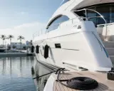 Un yacht blanc est amarré dans un port. Une corde est enroulée sur le pont. Le prix de l'entretien du bateau est élevé.