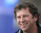 Lionel Lemonchois, skipper souriant, cheveux bouclés, sur fond bleu.