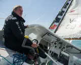 Un homme expérimenté, kito de pavant, tient la barre d'un voilier, concentré sur la course.
