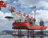Le bateau grue "Wind Ally" est prêt à installer une éolienne en mer. Sa structure imposante domine le port.