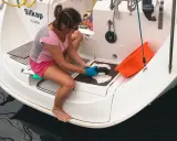 Préparation pour un tour du monde en voilier : une femme nettoie la plateforme arrière d'un bateau.