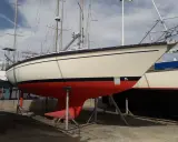 Voilier Dufour 31 sur bers. La coque est crème avec une bande bleue et une quille rouge vif.
