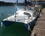 Un catamaran Hirondelle bleu et blanc, amarré à un ponton en bois, prêt pour une nouvelle aventure sur l'eau.